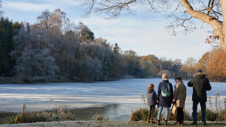 A family look out over the frosty lake at Nostell in Winter